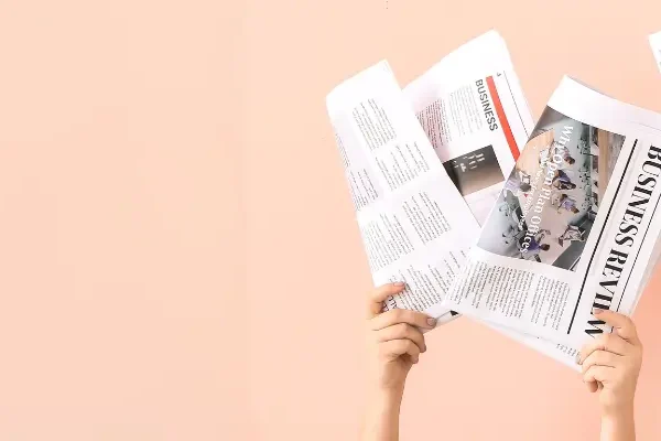 news papers being held up against a pink background